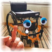 Bild 1 von 4: Der Rollstuhl ist im Stil eines Comics dargestellt, hat Augen und weint. Im Vordergrund, verpixelt, eine menschliche Hand, die dem Rolli den Mittelfinger zeigt.